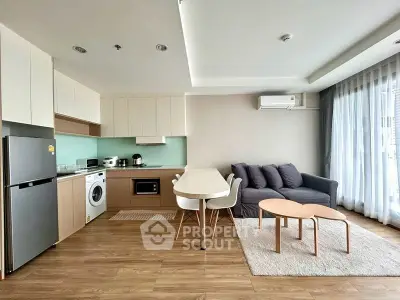 Modern open-plan living room with kitchen, featuring sleek furniture and natural light.