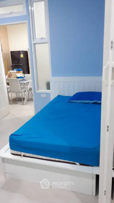 Cozy bedroom with blue accents and adjacent dining area, perfect for modern living.