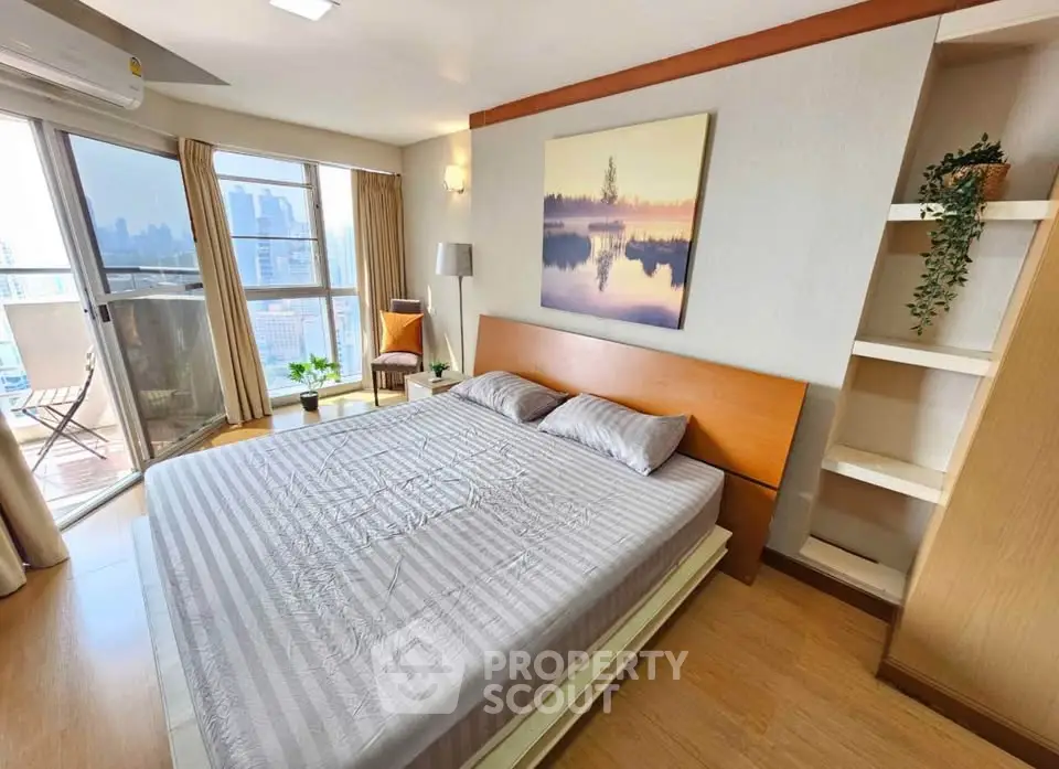 Spacious bedroom with balcony and city view, featuring modern decor and natural light.