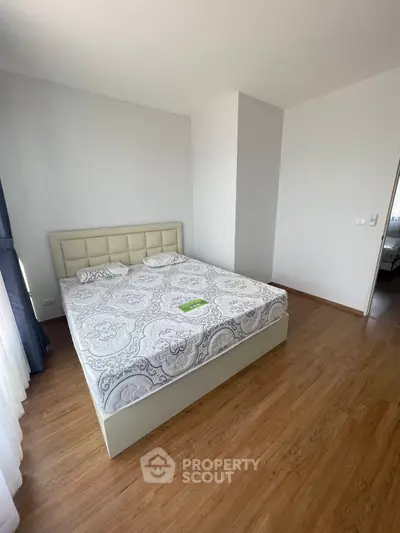 Spacious bedroom with elegant decor and wooden flooring in modern apartment.