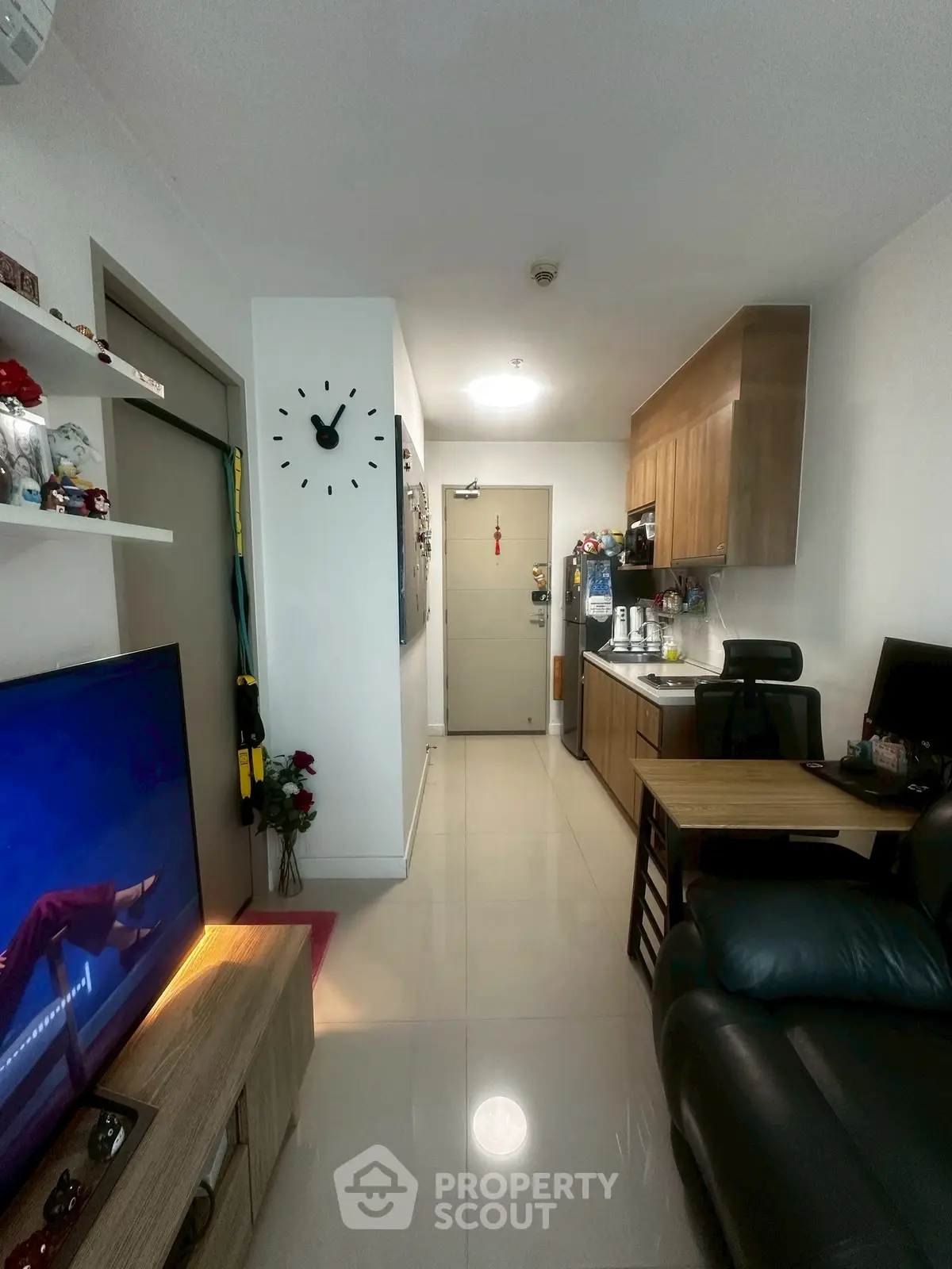 Modern living room with sleek kitchen, stylish decor, and cozy seating area in a compact apartment.