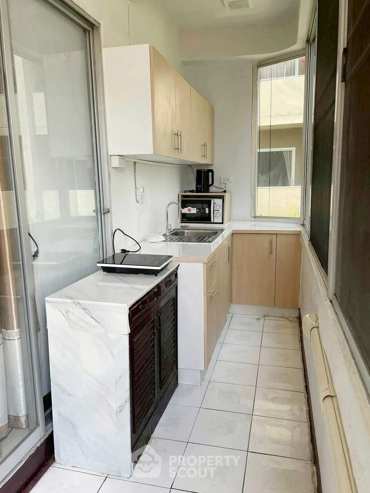 Compact kitchen with modern appliances and sleek cabinetry in a bright, narrow space.