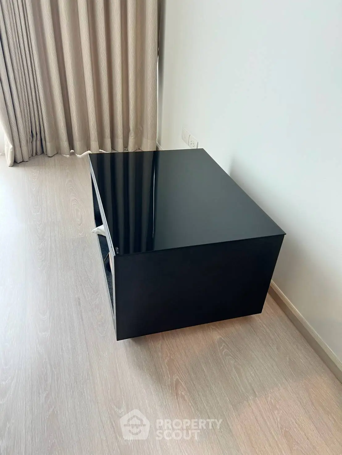 Modern minimalist side table in stylish apartment with wooden flooring and elegant curtains.