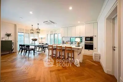 Spacious open-layout kitchen and dining area with modern appliances and elegant wooden flooring.