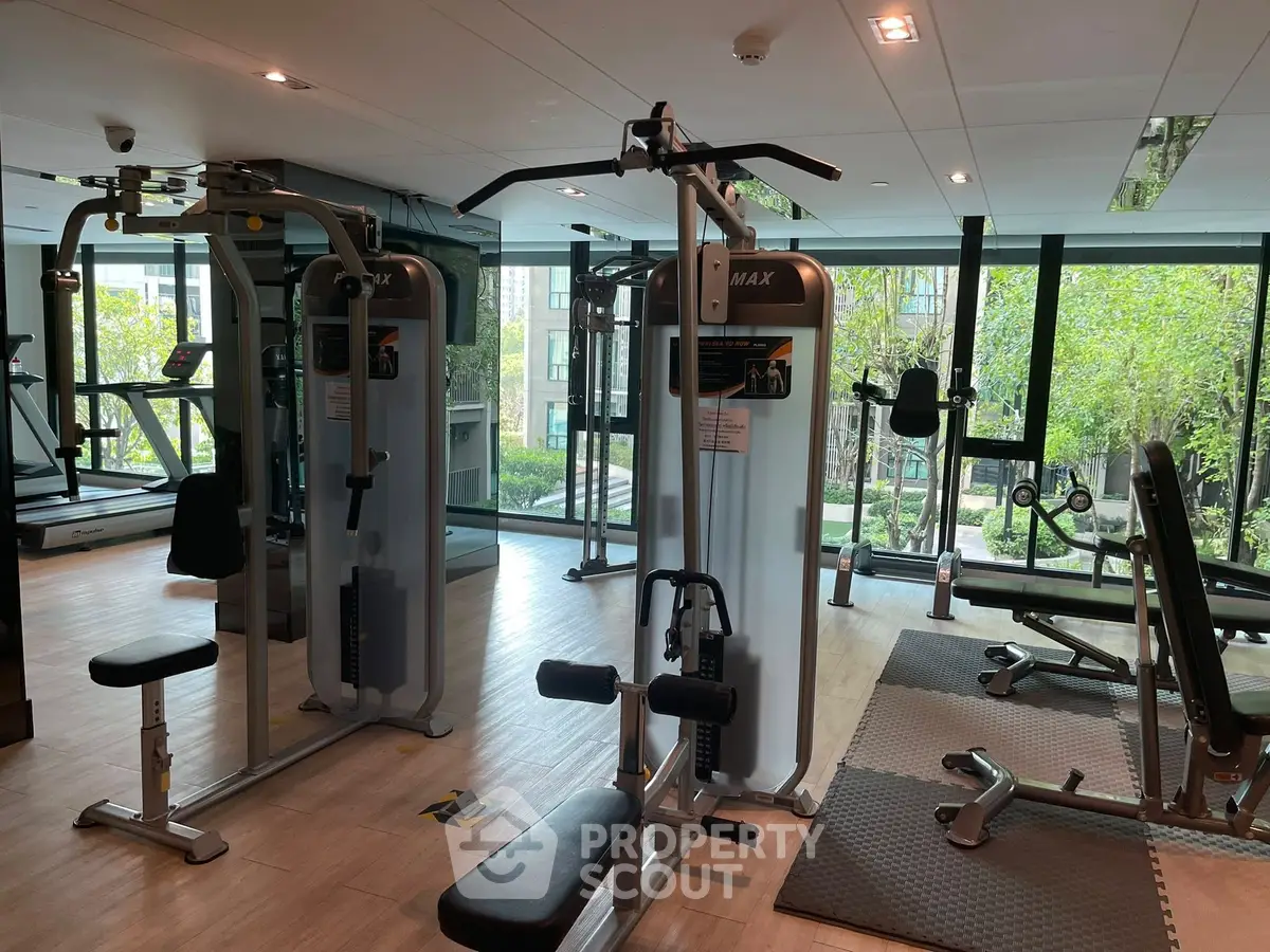 Modern gym with state-of-the-art equipment and large windows overlooking greenery.