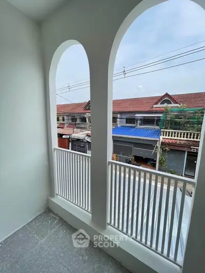 Charming balcony with arched openings overlooking residential street, perfect for relaxation.