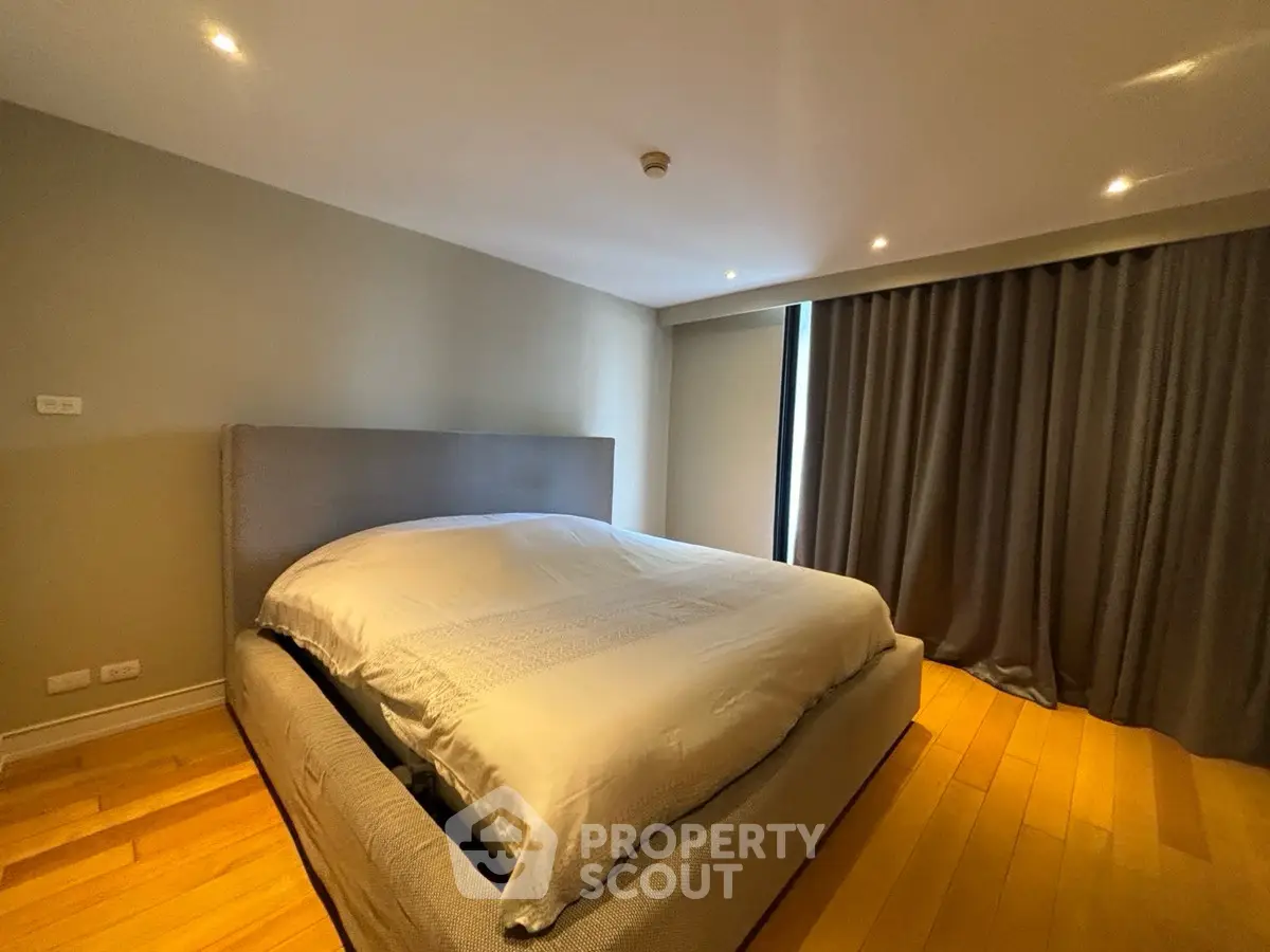 Spacious bedroom with modern design and cozy ambiance, featuring elegant lighting and wooden flooring.