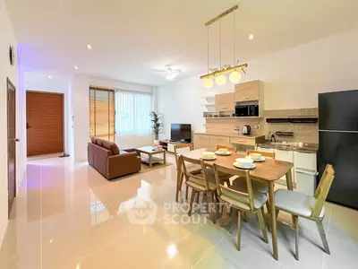 Spacious open-plan living room with modern kitchen and dining area, featuring sleek furniture and ample natural light.