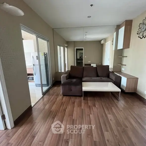 Spacious living room with modern decor and wooden flooring, featuring a cozy sofa and sleek furniture.