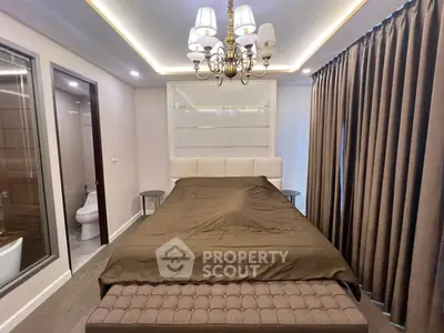 Luxurious bedroom with elegant chandelier and en-suite bathroom, featuring modern design and cozy ambiance.