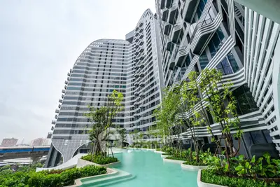 Stunning modern apartment building with unique architecture and lush poolside greenery.