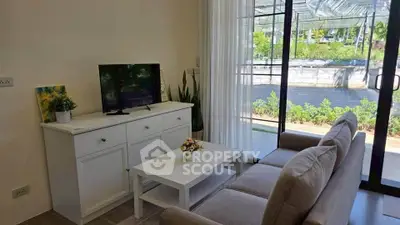 Charming living room with cozy sofa, modern TV setup, and garden view through large windows.
