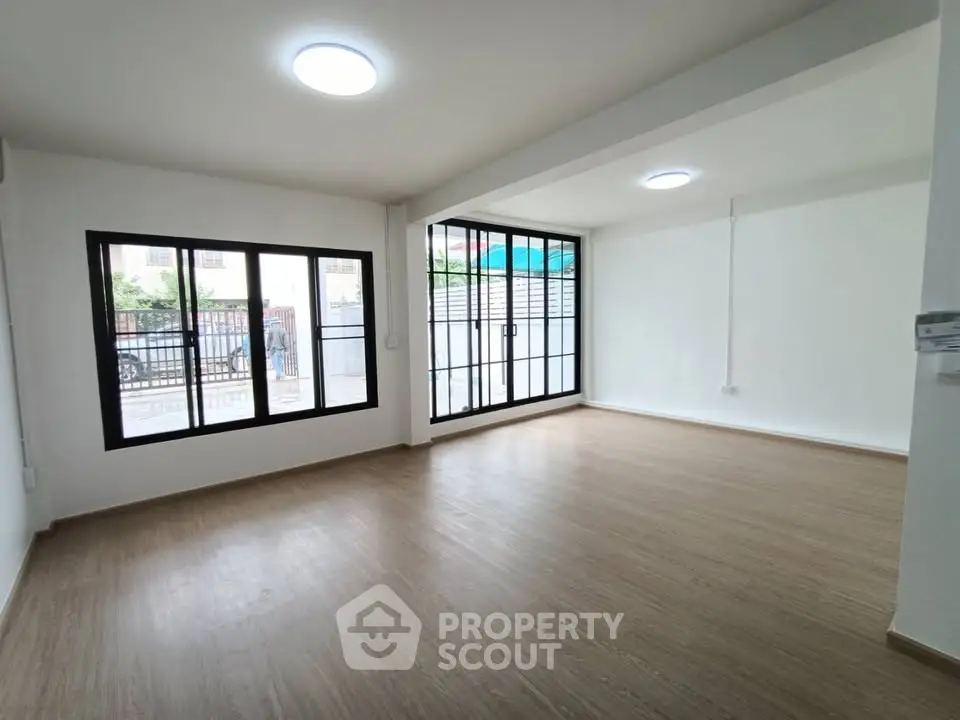 Spacious empty living room with large windows and wooden flooring