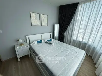 Modern bedroom with stylish decor and large window offering natural light.