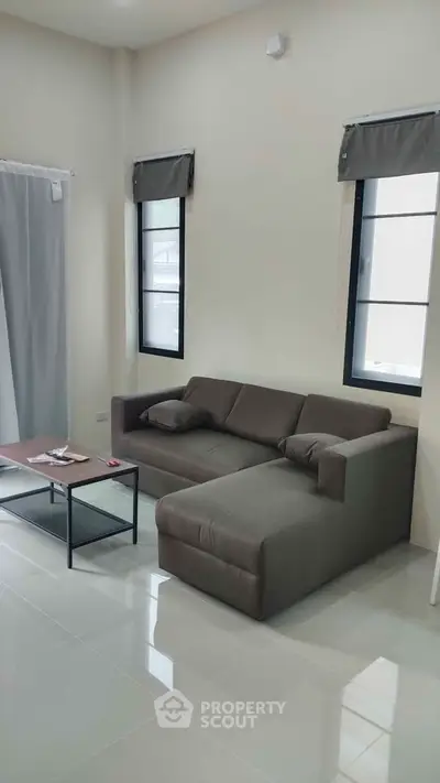 Modern living room with sleek gray sofa and minimalist decor, perfect for relaxation and entertaining.