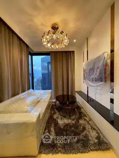 Luxurious living room with modern chandelier and city view, featuring elegant decor and plush carpeting.