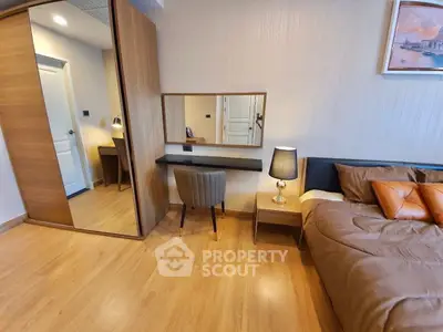 Modern bedroom with wooden flooring, stylish mirror, and cozy bed setup.