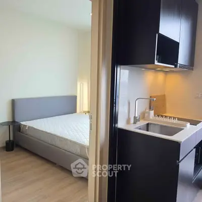 Modern studio apartment with compact kitchen and cozy bedroom featuring sleek design and efficient layout.