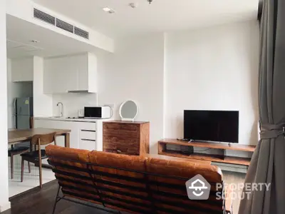 Modern open-plan living room with kitchen, featuring sleek furniture and natural light.