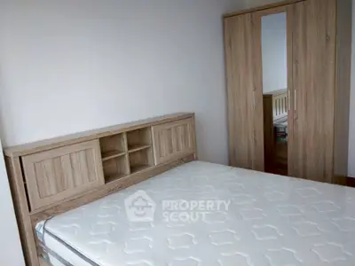 Spacious bedroom with wooden wardrobe and bed frame, perfect for modern living.