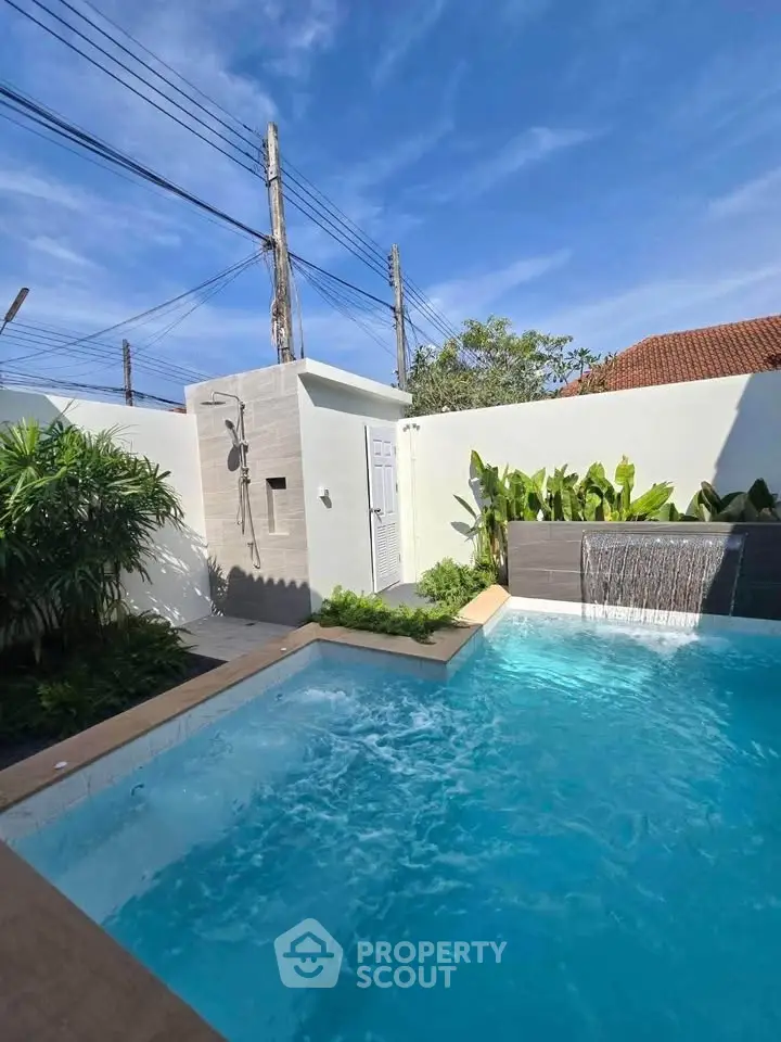Luxurious private pool with waterfall feature in a serene backyard setting.