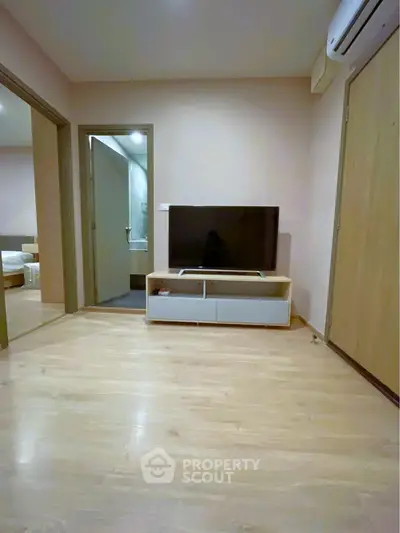 Modern living room with sleek TV stand and wooden flooring, adjacent to bedroom and bathroom.