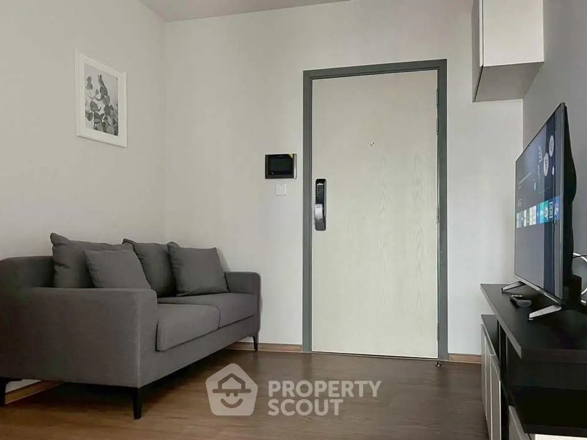 Modern living room with sleek gray sofa and wall-mounted TV, perfect for cozy relaxation.
