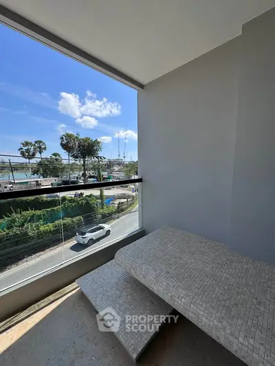 Stunning balcony view with modern design overlooking a scenic coastal road and lush greenery.