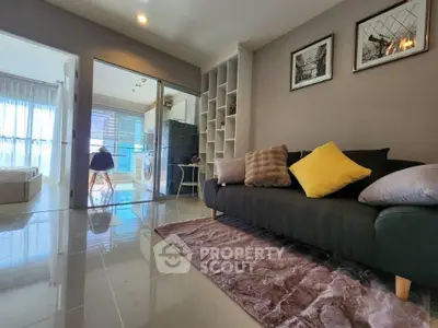 Modern living room with sleek sofa and open view to bedroom and kitchen area.