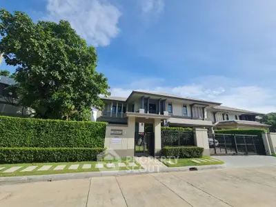 Modern two-story house with lush greenery and gated entrance