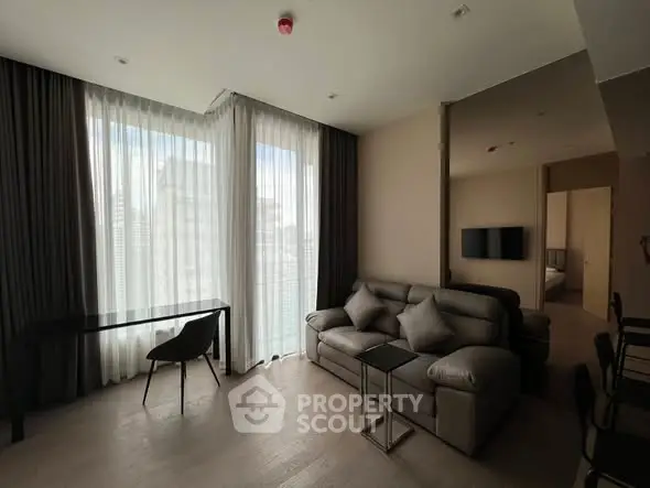 Modern living room with sleek furniture and large windows offering city views.