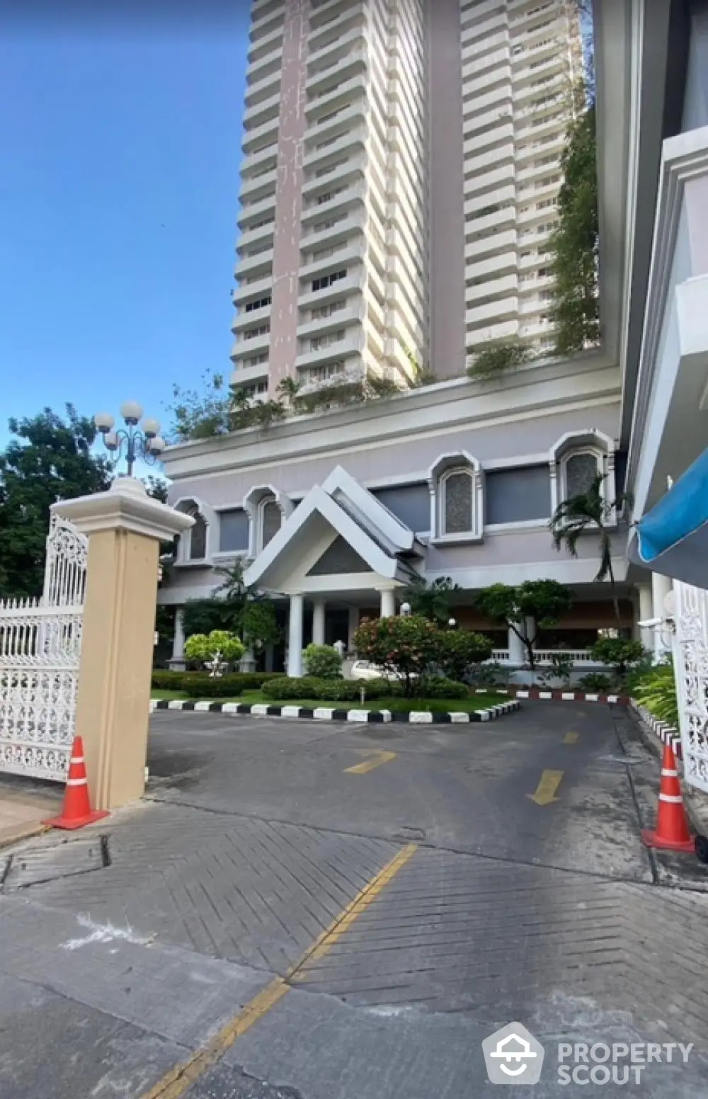 Elegant high-rise condominium tower with a grand entrance, lush greenery, and a welcoming driveway, showcasing luxury urban living in a serene environment.