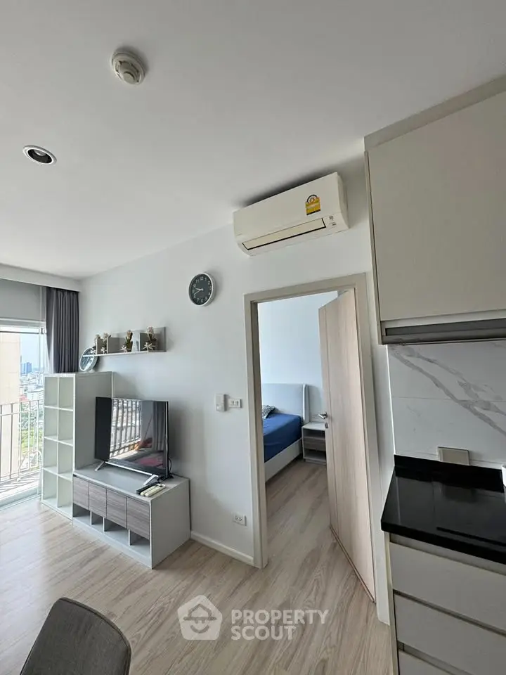 Modern apartment interior with open layout, featuring a cozy living area and a glimpse into the bedroom.