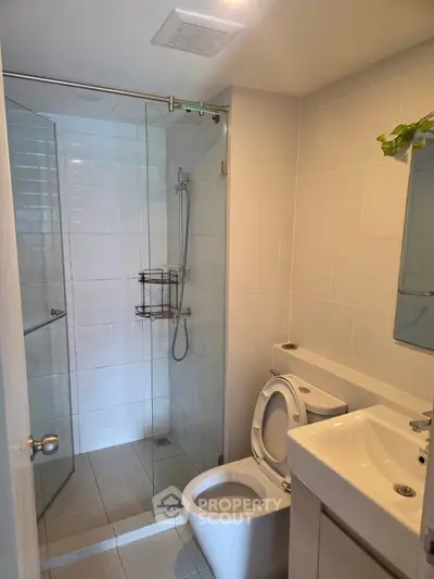 Modern bathroom with glass shower and sleek fixtures in contemporary apartment.