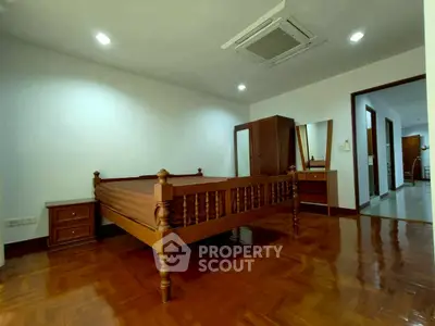 Spacious bedroom with wooden flooring and elegant furniture