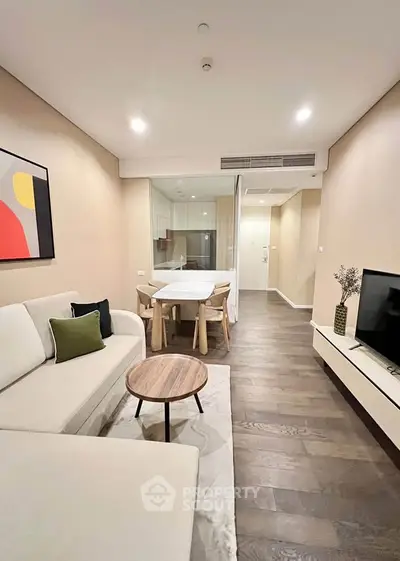Modern living room with stylish decor and open layout, featuring a cozy sofa and sleek dining area.