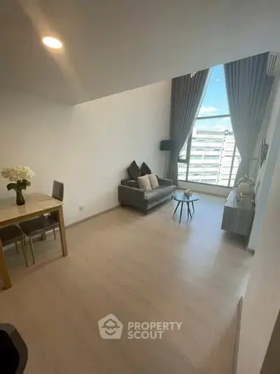 Spacious modern living room with large window and city view, featuring elegant decor and natural light.