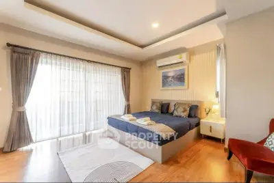 Spacious bedroom with modern decor and large windows for natural light.