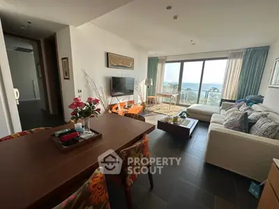Spacious living room with ocean view, modern decor, and elegant dining area in luxury apartment.