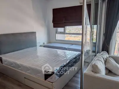 Modern bedroom with large window and city view, featuring a cozy bed and stylish decor.