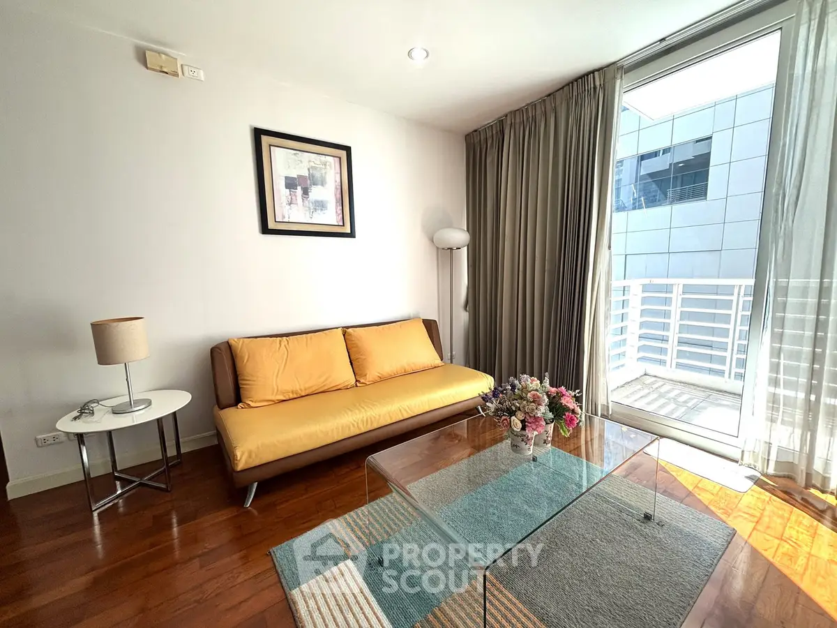 Modern living room with stylish decor and balcony access, featuring a cozy sofa and elegant glass coffee table.