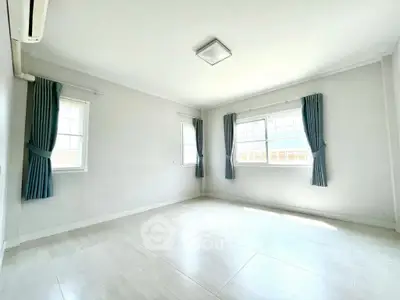 Spacious and bright empty room with large windows and elegant curtains, perfect for customization.