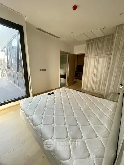 Spacious bedroom with large window and modern wardrobe in luxury apartment