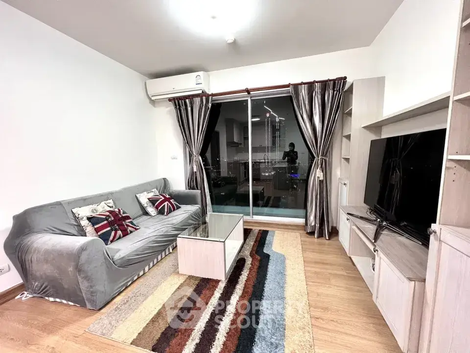 Modern living room with city view, featuring stylish decor and large TV setup.