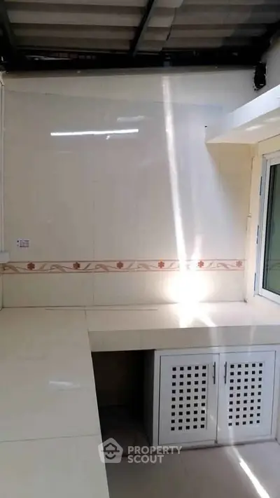 Bright kitchen with white countertops and tiled backsplash, featuring a closed layout.