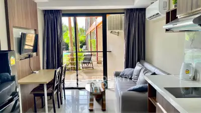 Modern living room with pool view, stylish furniture, and open kitchen layout in a luxury apartment.