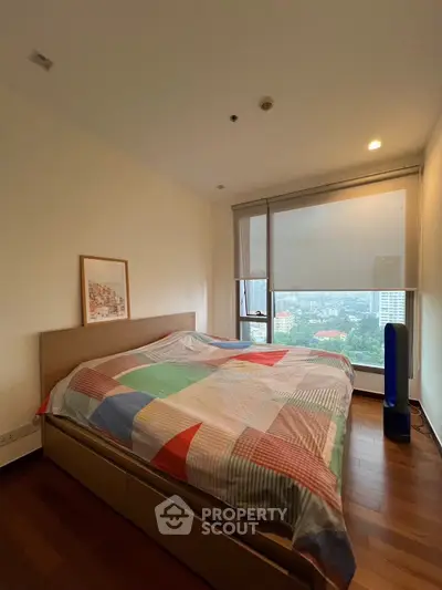 Spacious bedroom with large window offering stunning city view, featuring a cozy bed and elegant wooden flooring.