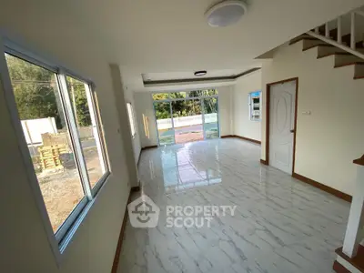 Spacious living room with large windows and elegant tile flooring, offering a bright and airy atmosphere.