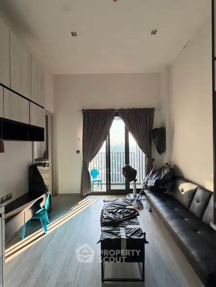 Modern living room with high ceiling and balcony view, featuring sleek furniture and natural light.