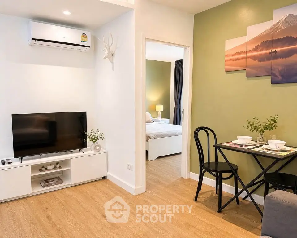 Modern living room with TV, air conditioning, and dining area leading to a cozy bedroom.